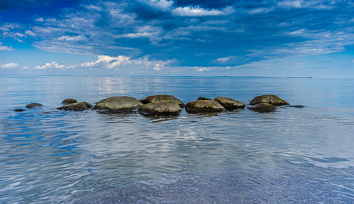 Große Steine im Wasser Große Steine im Wasser; Im glatten Wasser ragen eine handvoll Steine aus dem Wasser.